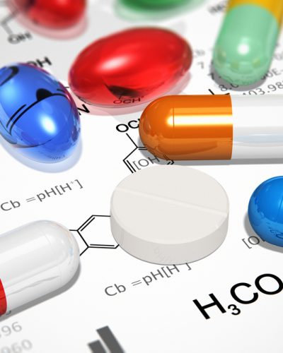 Pharmacy concept: macro view of heap of color pills and tablets over chemical formulas on white background