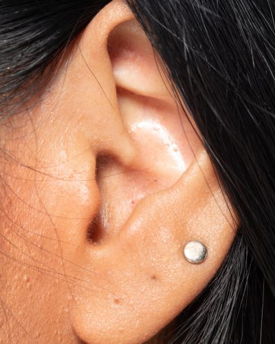 Body Part of Asian female Ear left side, Woman ears with fashion earrings decorate and some hair, studio lighting close up skin on Face